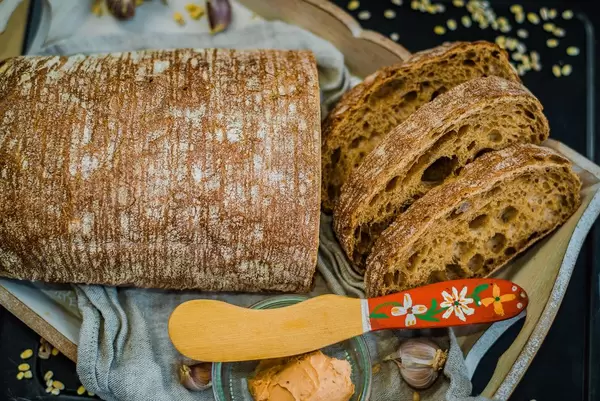 Blick von oben auf frisch gebackenes Ciabatta mit Frischkäse und Knoblauch auf Holztablett
