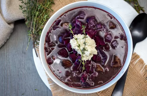 Blick von oben auf rote Borschtsch Suppe aus Rotkohl und Suppenfleisch mit Rosmarin