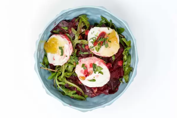 Blick von oben auf Salat aus roter Bete, Apfel, Rucola und Ziegenkäse vor weißem Hintergrund
