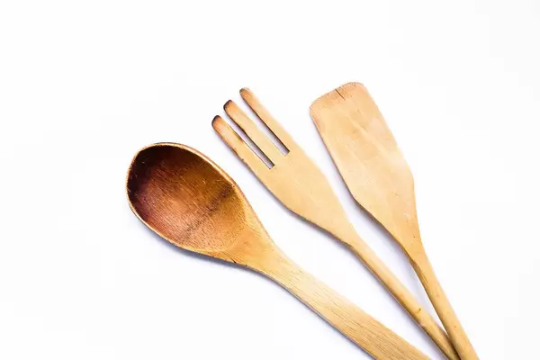 Blick von oben auf Sortiment an Kochbesteck aus Holz wie Kochlöffel und Spatel vor weißem Hintergrund