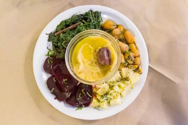 Blick von oben auf vegetarisches Favapüree mit roter Bete, weißen Bohnen, Spinat und Kartoffeln