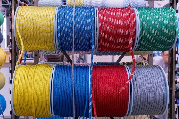 Blick von vorne auf Rollen mit einfarbigen und gemusterten Schiffstauen in verschiedenen Farben