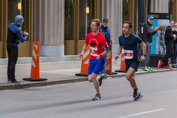 Blind participant at the Chicago Marathon 2019 running next to another athlete. The two hold a cord that connects them