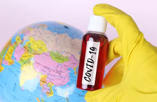 Blood sample in test tube with COVID-19 text and globe in the background