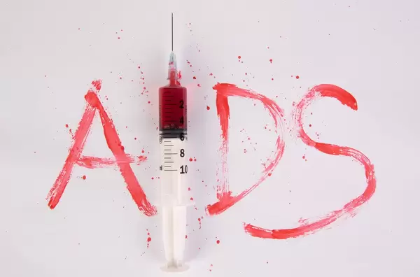 Bloody word AIDS with injection needle on white background