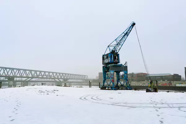 Blue abandoned crane covered with graffiti standing out in snow covered industrial district of Hamburg