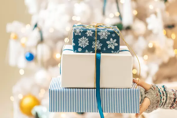 Blue and white gift boxes on blurred background of christmas tree with garlands