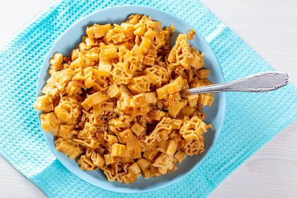 Blue bowl full of pasta with sauce and fried minced meat. Top view
