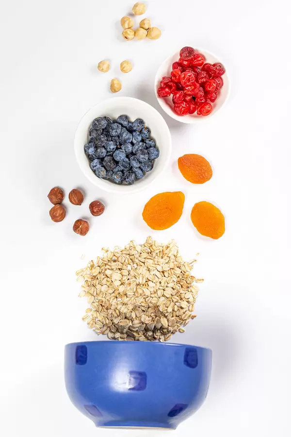Blue bowl with raw oatmeal, dried berries and nuts, top view
