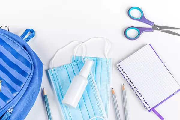 Blue briefcase, school items and personal protective equipment during quarantine