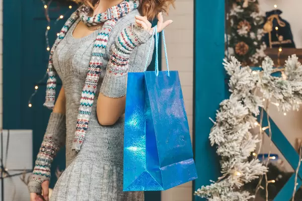 Blue gift bag in female hand, christmas shopping concept