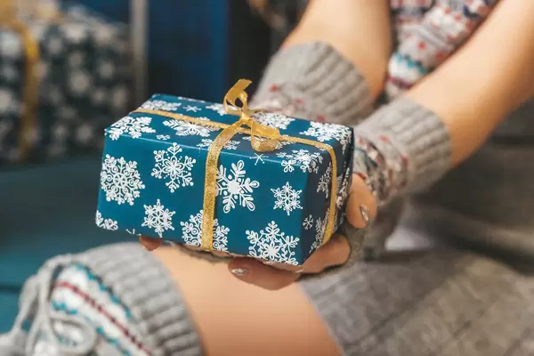 Blue gift box with gold ribbon in women's hands, close-up