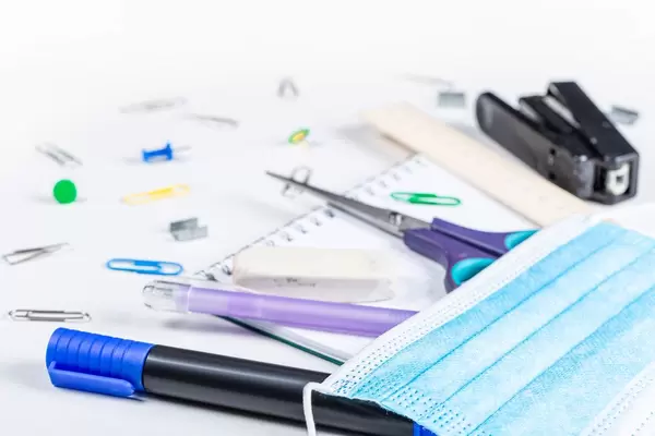 Blue medical mask with school things on a white background. Quarantine preparation concept