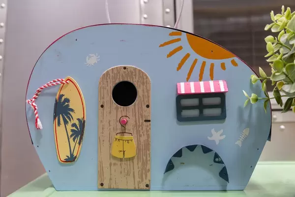 Blue miniature caravan with beach flair, a surfboard and summer painting