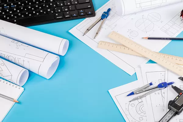 Blueprints and blueprint rolls with a drawing instruments on the worktable