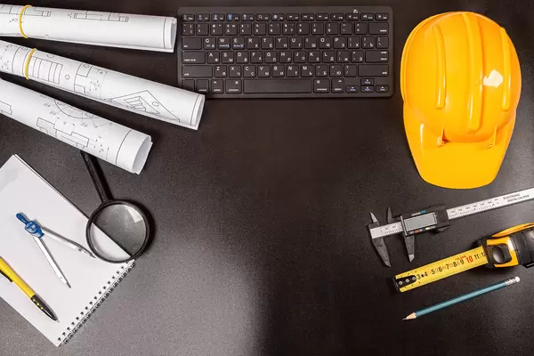 Blueprints, drawing tools, hard hat and keyboard on a dark background