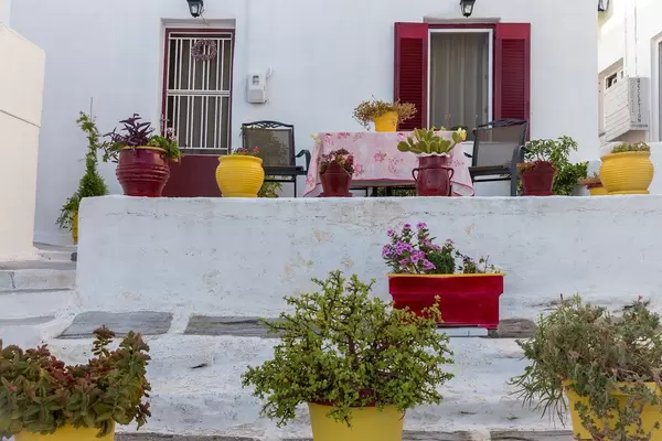 Blumentöpfe und Pflanzen auf einer Veranda eines landestypischen Kalksteinhauses in der Hafenstadt Naoussa, Griechenland