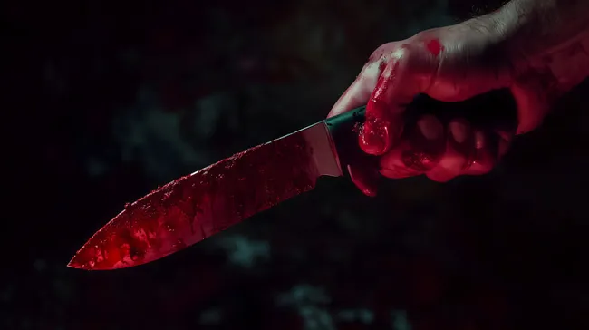 Blutverschmierte Hand mit messendem Küchenmesser