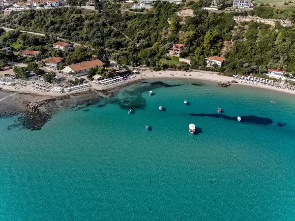 Boats, beach and hill with hotels in Afitos, Greece