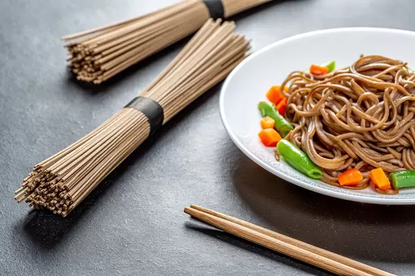 Boiled and raw buckwheat soba noodles on a black background