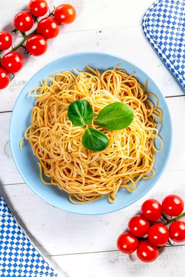 Boiled spaghetti with cherry tomatoes on a white wooden table. Top view (Flip 2019)