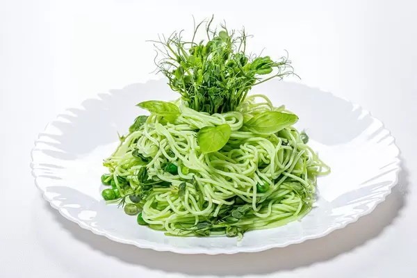 Boiled spaghetti with fresh pea sprouts and young peas on a white plate (Flip 2019)