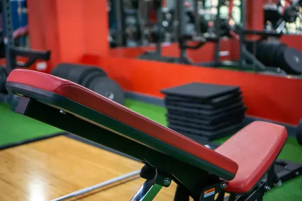 Bokeh Photo of Adjustable Gym Bench with Different Exercise Equipment in a Fitness Center