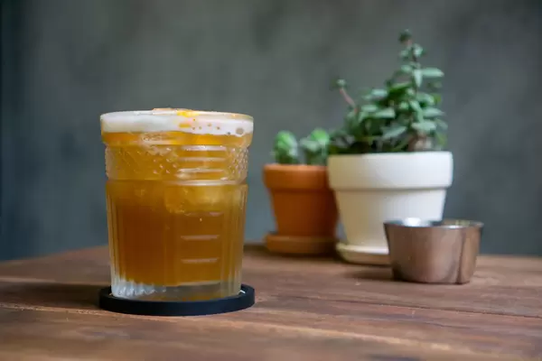 Bokeh Photo of Orange Iced Tea with Cinnamon in a Cocktail Glass with Ash Tray and Miniature Plants in the Background