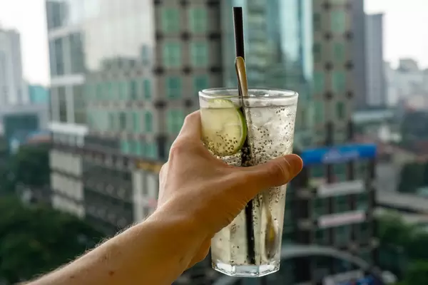 Bokeh Photo of Person holding a Glass of Lemonade with Lime, Chia Seeds and Aloe Vera