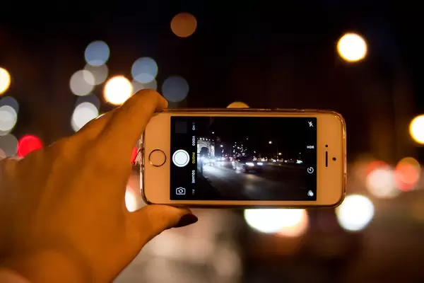 Bokeh Photo of Person taking a Night Shot of Bucharest City with Smartphone