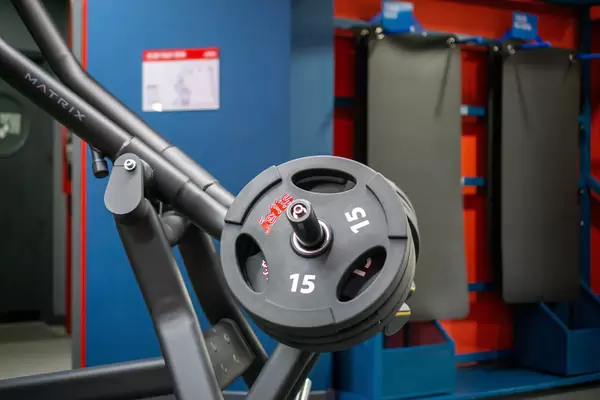 Bokeh Photo of Several Weight Plates on a Lat Pull Down Machine with Yoga Mats in the Background