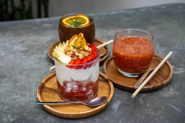 Bokeh Photo of Strawberry Yogurt with fresh Fruits with Hot Strawberry Tea and Burnt Orange Cold Brew Coffee in the Background
