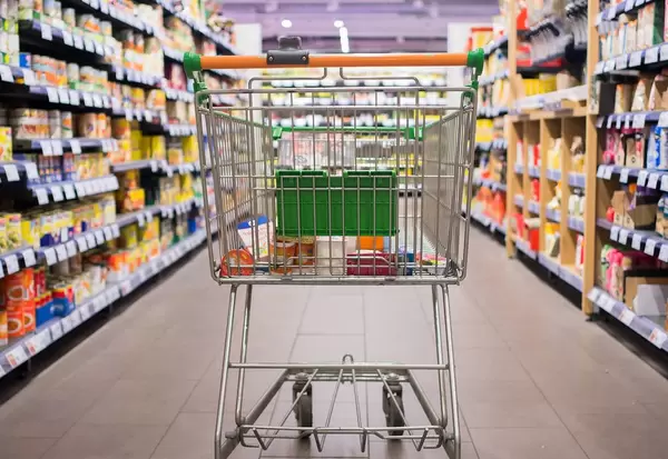 Bokeh Rear View Photo of Shopping Cart standing in empty Grocery Store Aisle