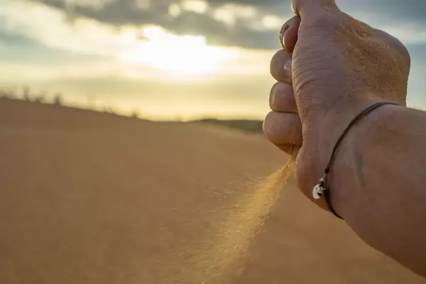 Bokeh Shot of a Hand dropping Sand in the Desert with Sunset in the Background  Flip 2019