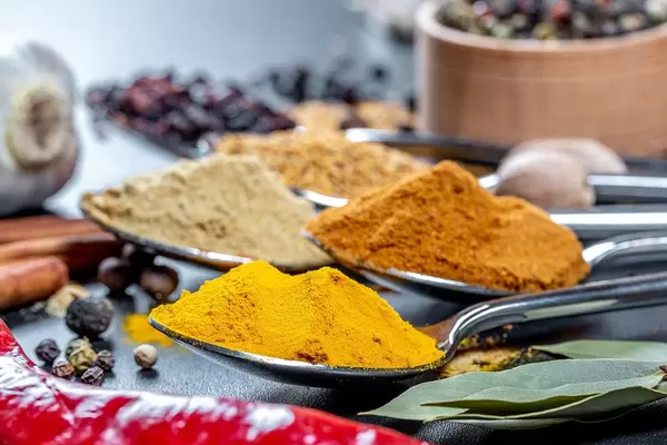 Bokeh von Gewürzpulvern auf Löffeln - Kurkuma, Curry, Knoblauch