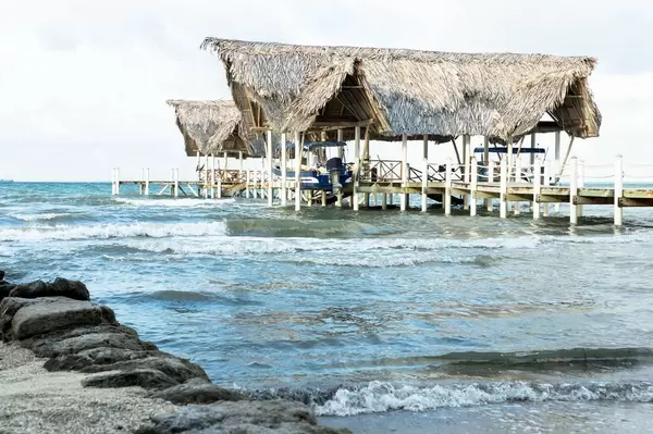 Bootssteg mit Palmendach und anlegende Boote