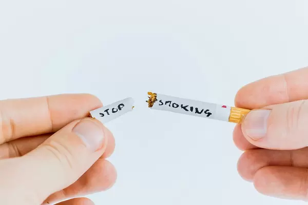Borken cigarettes with stop smoking writing between a man's hands