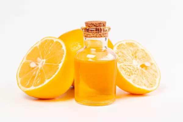 Bottle of essential oil from lemon and fresh ripe lemons on white