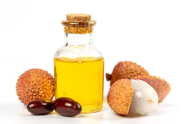 Bottle of lychee essential oil with fresh fruits lychee