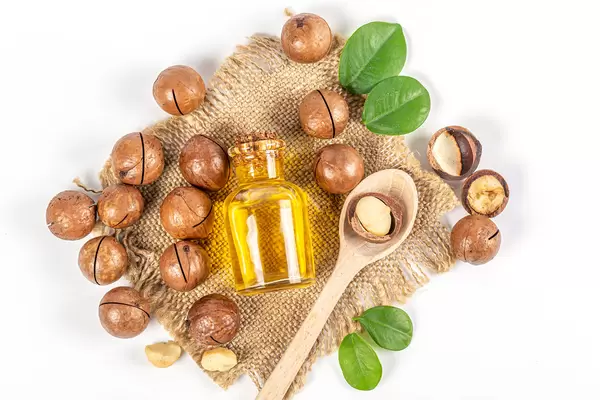 Bottle with oil and macadamia nuts with burlap and wooden spoon, top view