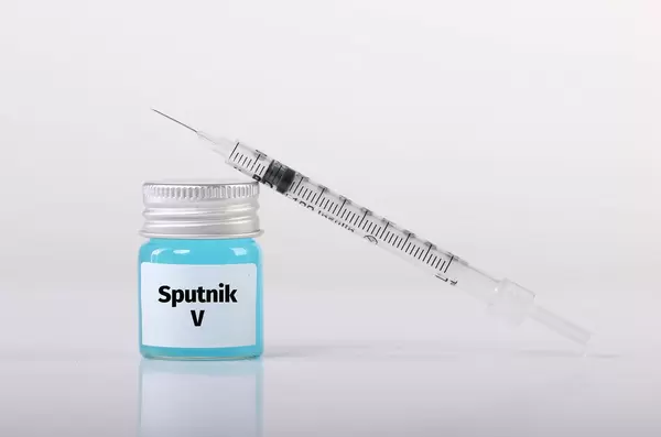 Bottle with Sputnik V vaccine and syringe on white background
