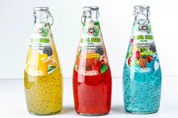 Bottles with fruit cocktails and Basil seeds on white background