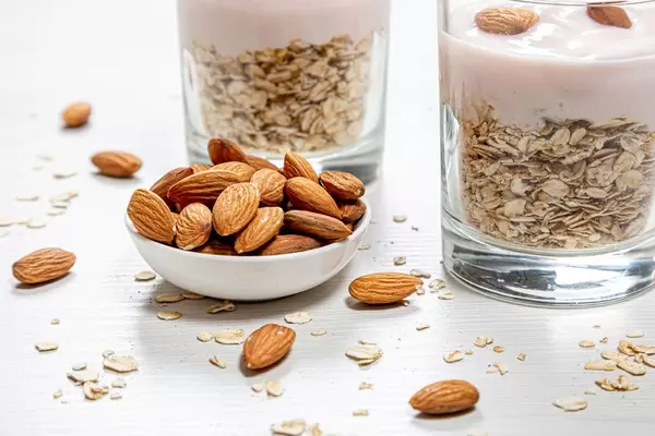 Bowl full of almonds and oatmeal porridge behind
