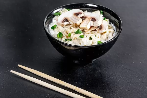 Bowl of cheese and mushroom soup with pasta and herbs