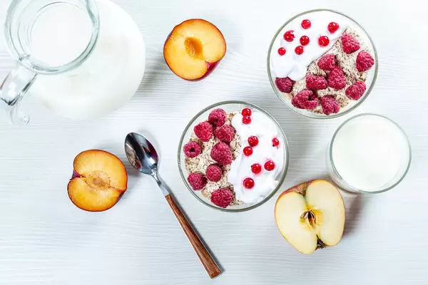 Bowl of healthy oatmeal with fresh berries and fruits with milk on white wooden background (Flip 2019)