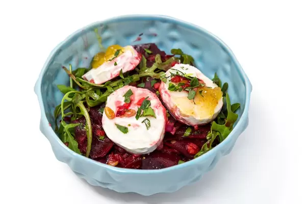 Bowl of lettuce beetroot, whole rucola leaves and poached eggs with white background