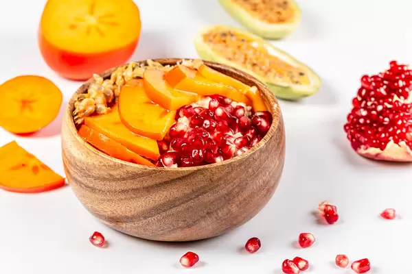 Bowl of oatmeal with pomegranate, persimmon and kuruba