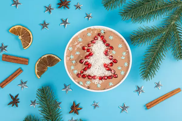 Bowl with christmas oatmeal on blue background with new year decor, top view
