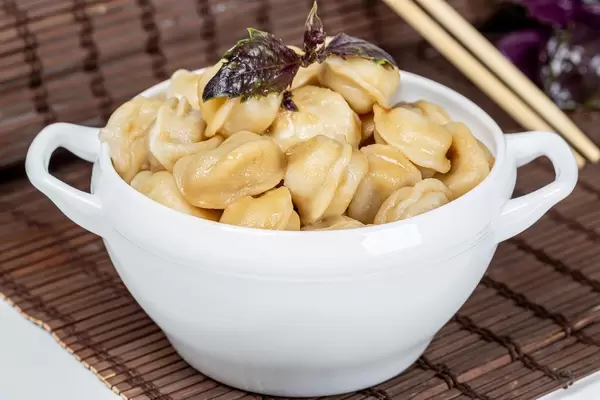 Bowl with hot boiled dumplings and red basil leaves