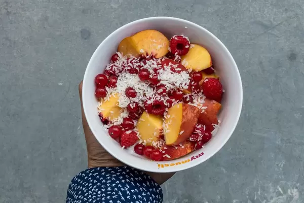 Bowl with raspberries, currants, peach and shredded coconut